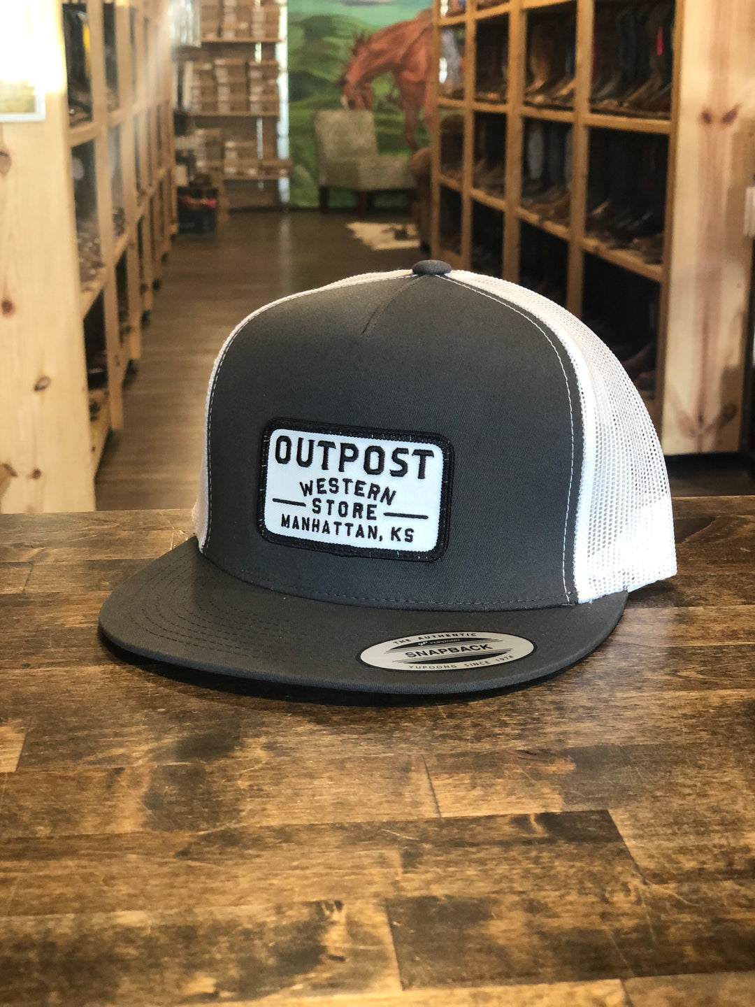 Grey fabric front, white mesh back, Outpost logo patch, Yupoong Trucker Cap